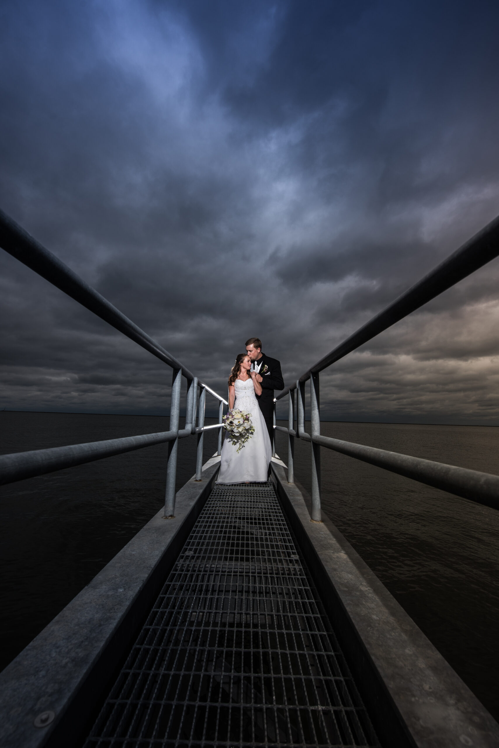 Couple on their wedding day on a pier by the water