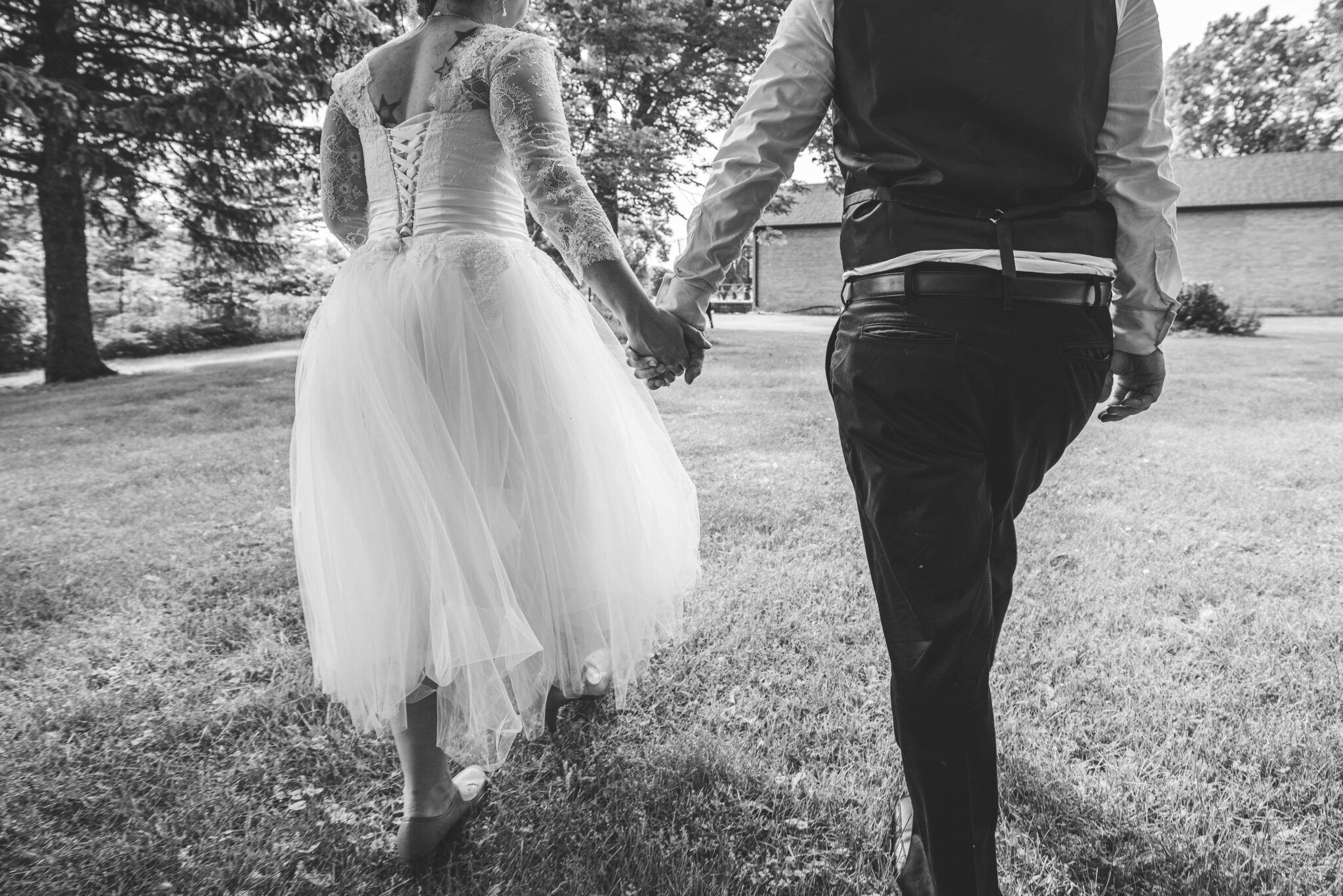newly wed couple holding hands and walking from behind in green bay on their wedding day